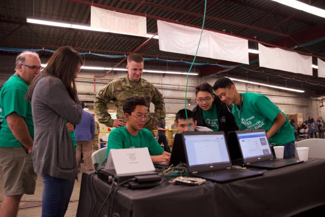 adults supervise students working on multiple computers